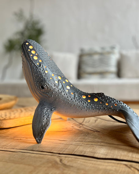 Whale-shaped lamp on a wooden surface with a blurred living room background