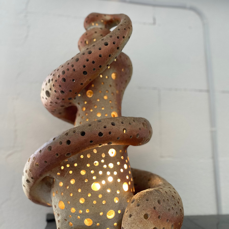 Ceramic sculpture with a textured surface and embedded lights on a white background