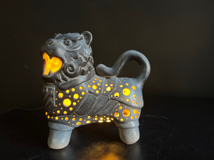 Ceramic lion figurine with glowing yellow interior on a dark background