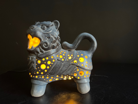 Ceramic lion figurine with glowing yellow interior on a dark background