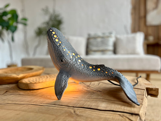 Whale-shaped lamp on a wooden surface with a blurred living room background