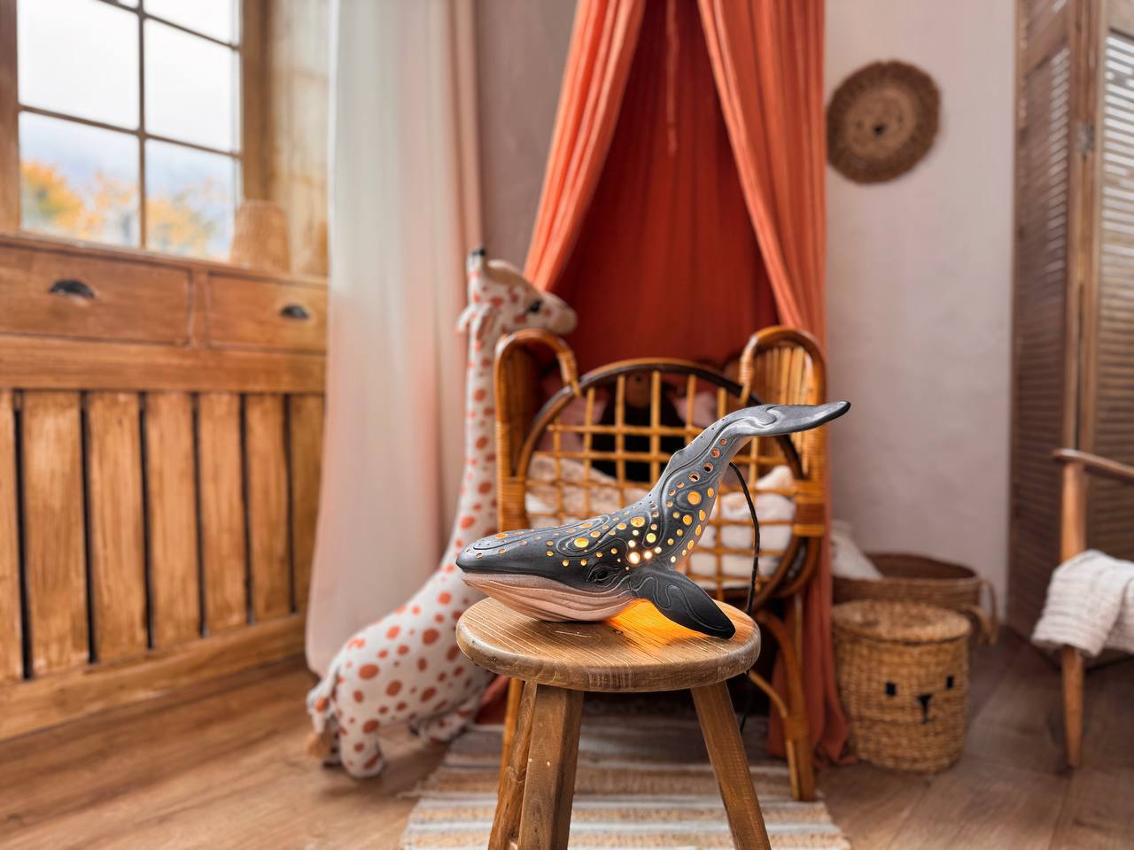 Nursery interior with wooden furniture, a whale-shaped lamp, and decorative elements.