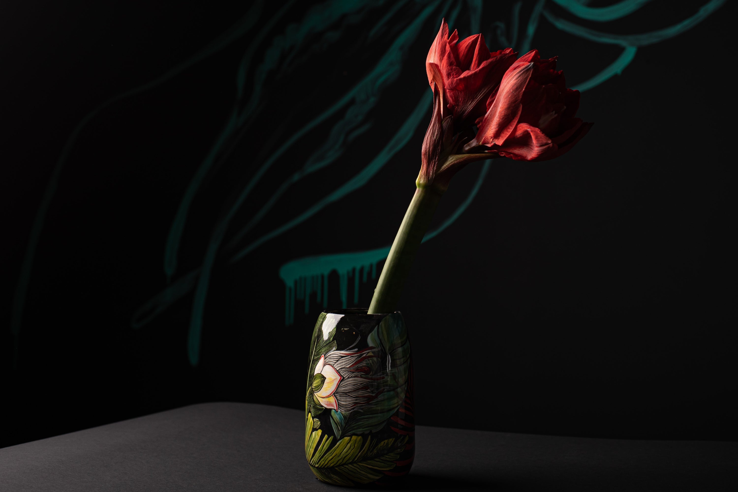 Red flower in a decorated vase against a dark background