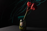 Red flower in a decorated vase against a dark background
