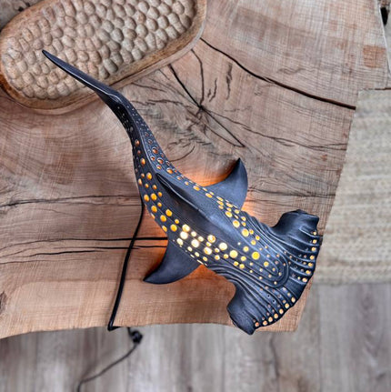 Decorative fish sculpture on a wooden surface with a textured background
