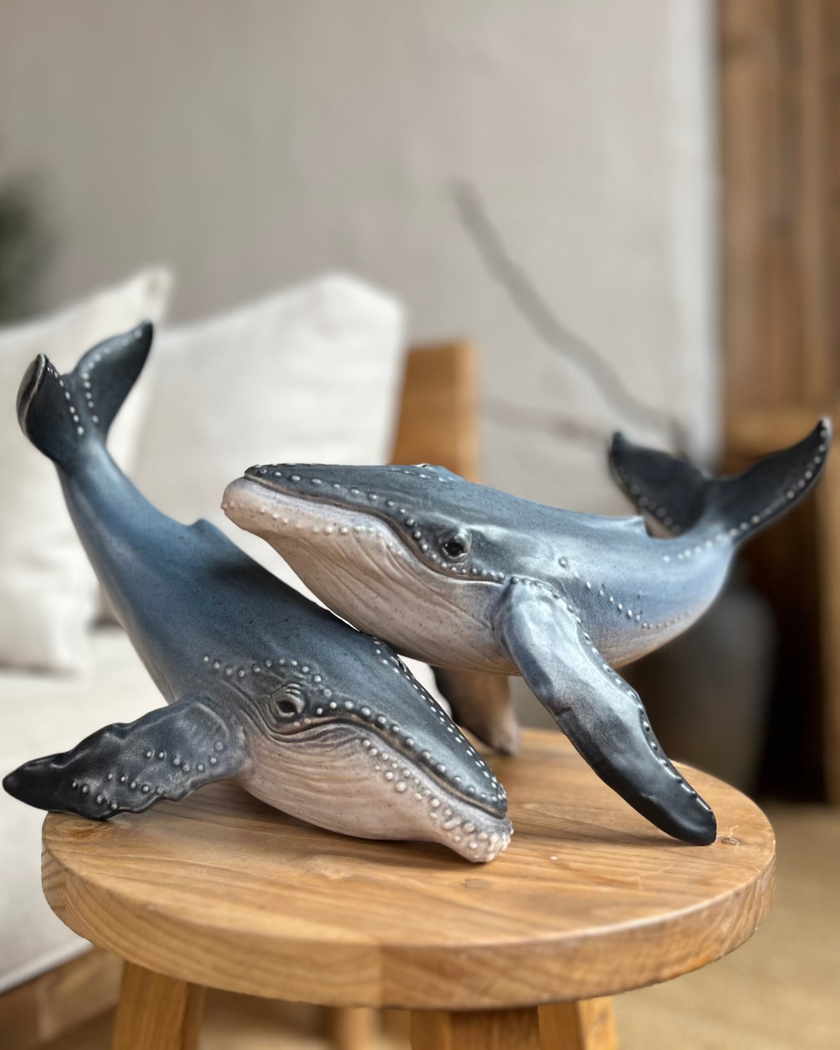 Two whale figurines on a wooden table in a living room setting.