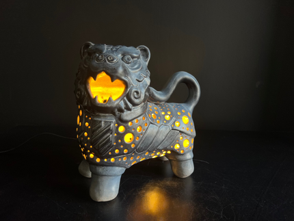 Ceramic lion-shaped lantern with glowing interior on a dark background