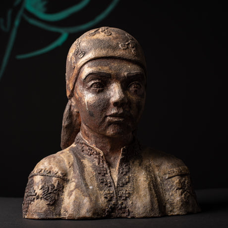 Ceramic bust of a person wearing a headscarf on a dark background