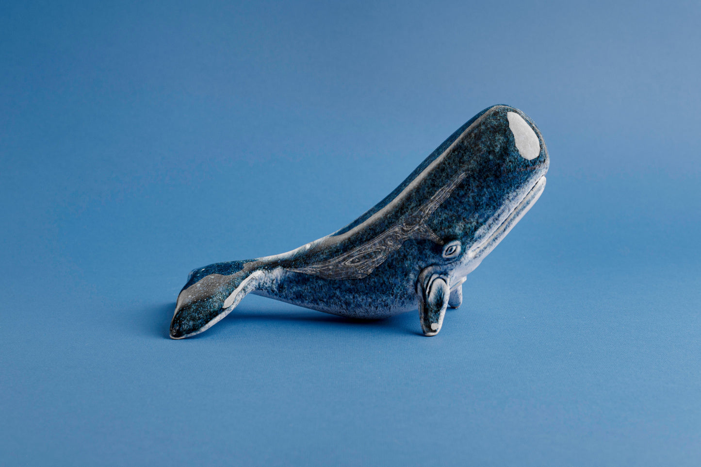 Blue ceramic whale figurine on a blue background