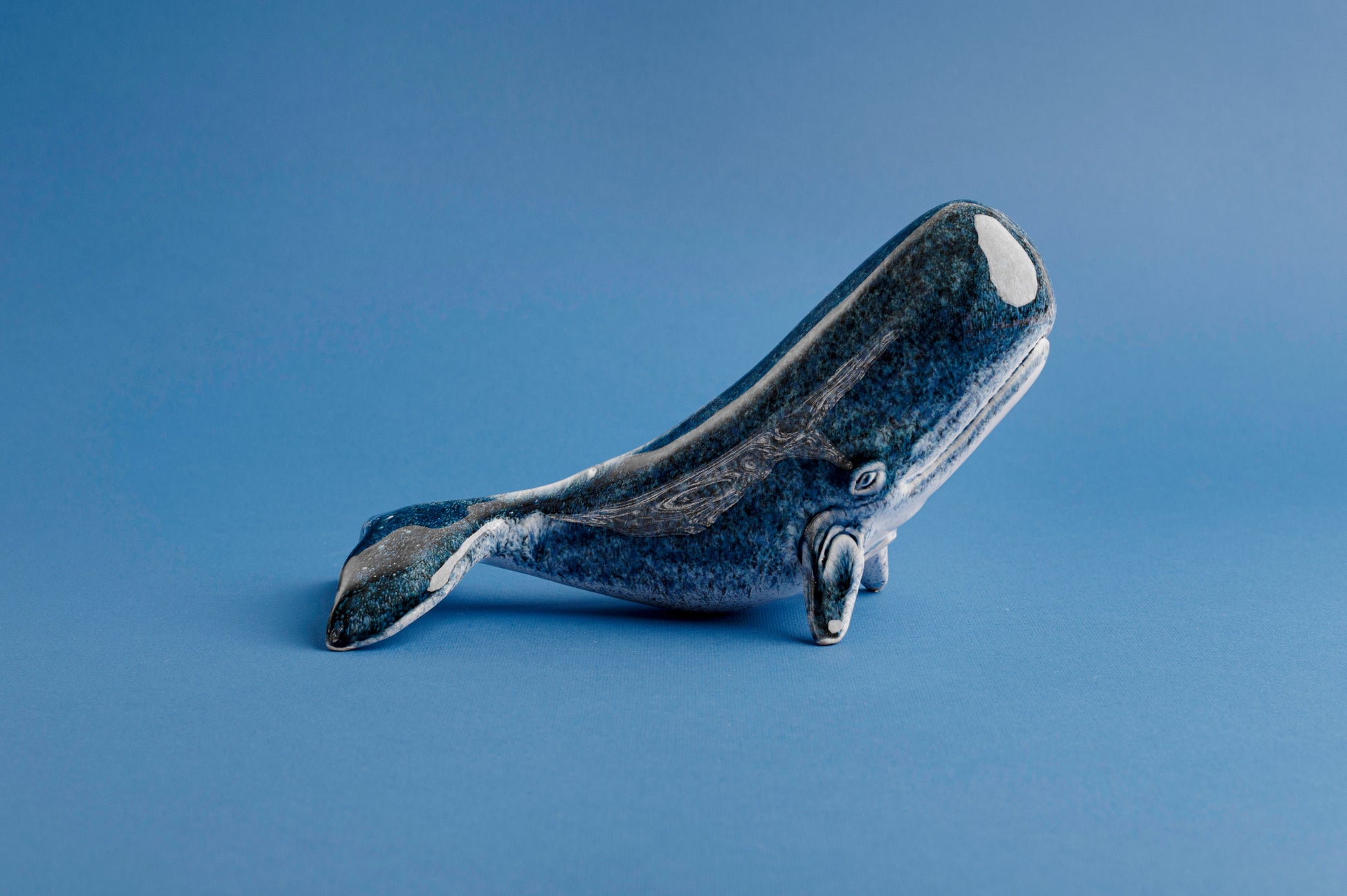 Blue ceramic whale figurine on a blue background