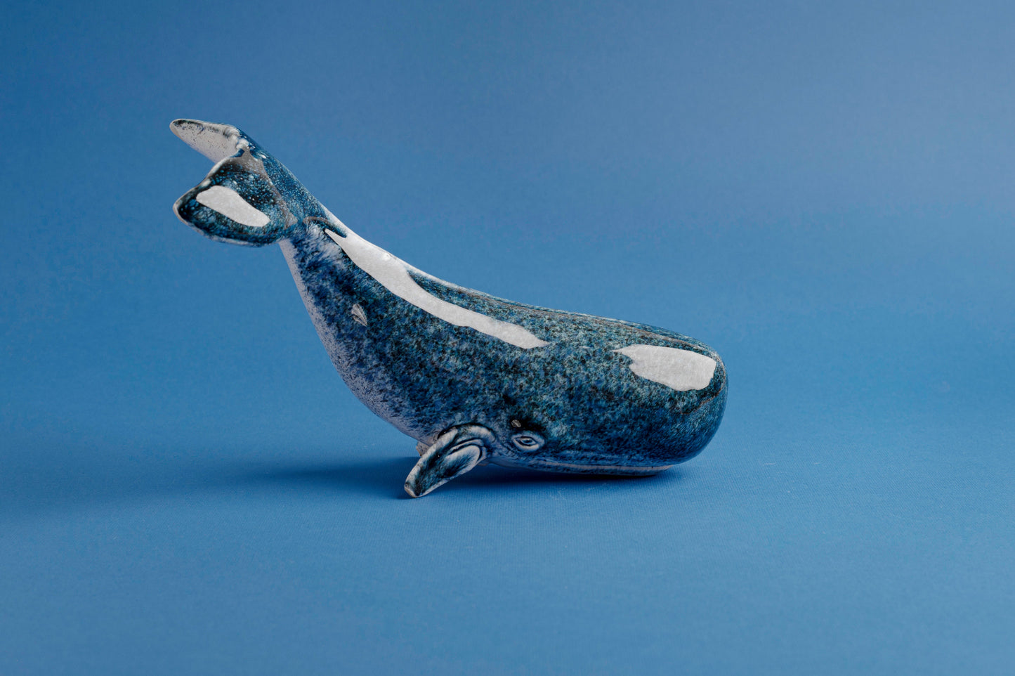 Blue ceramic whale figurine on a blue background