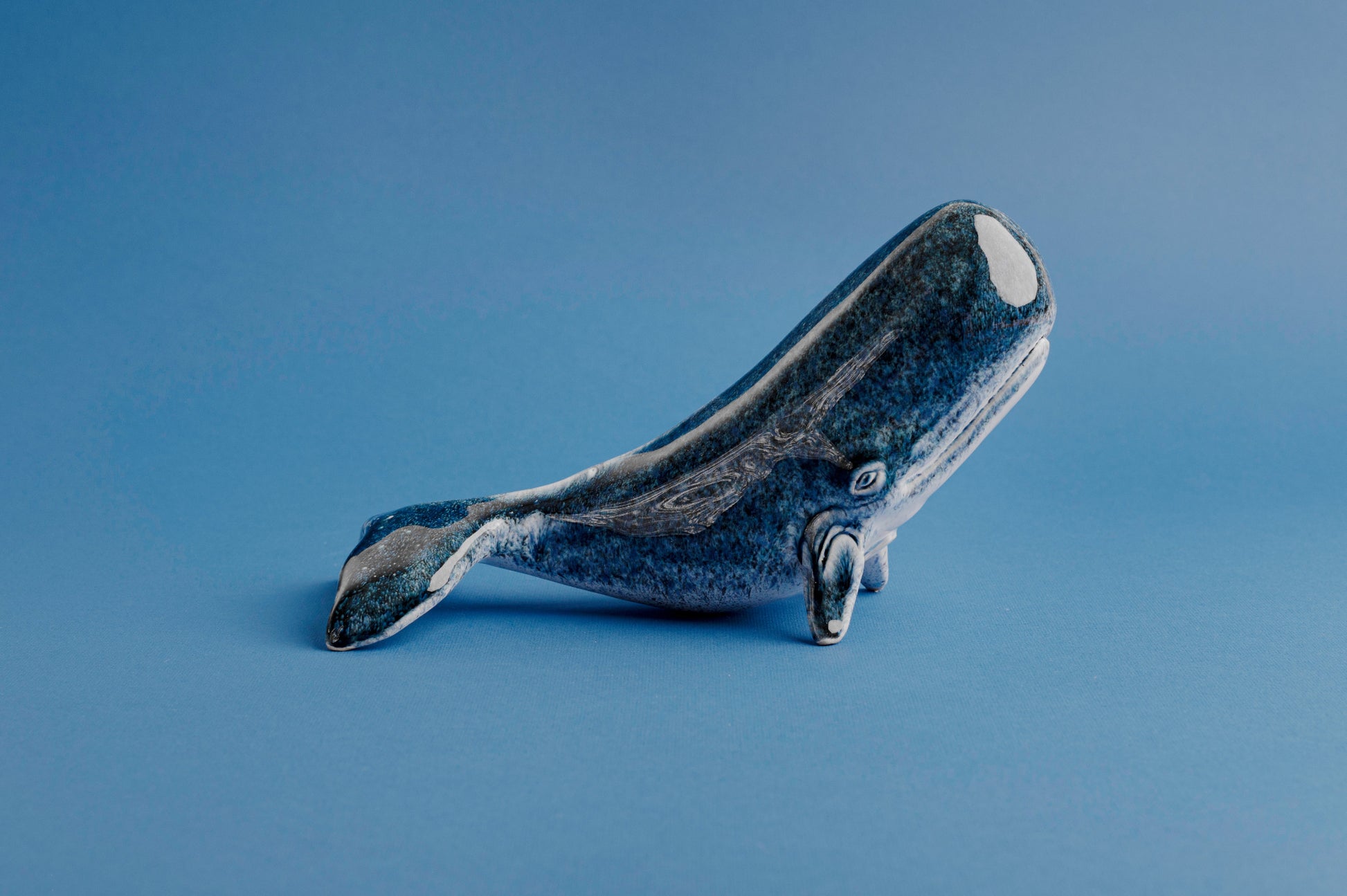 Blue ceramic whale sculpture on a blue background