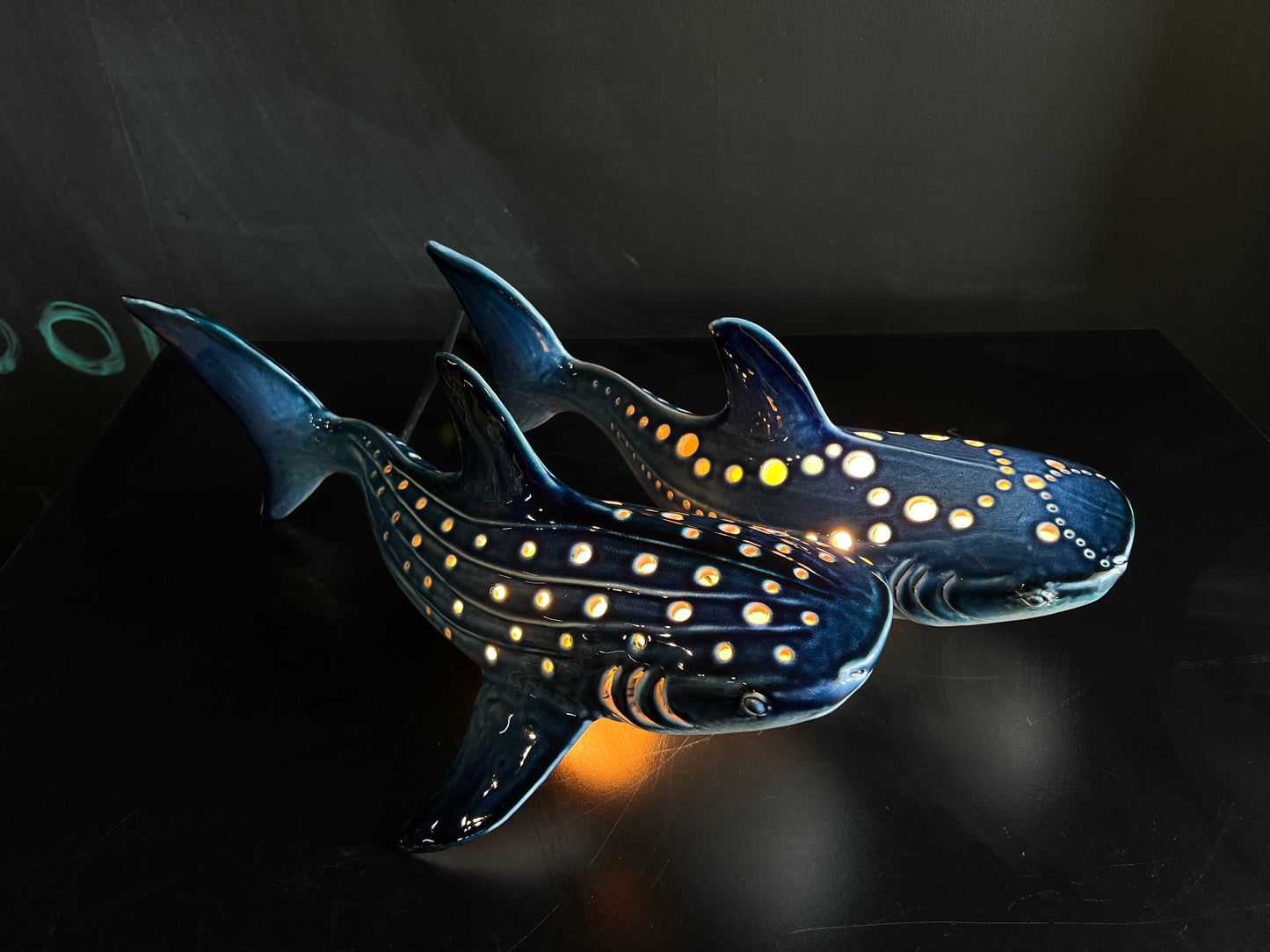 Decorative whale shark sculptural lamp with glowing interior on a dark background