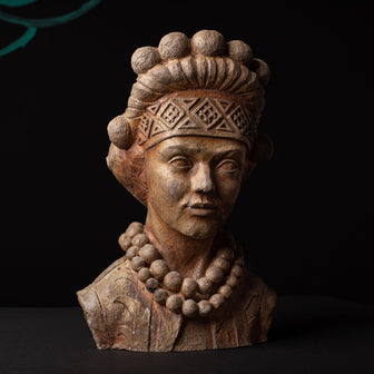 Ceramic bust of a figure with intricate headpiece and necklace on a dark background