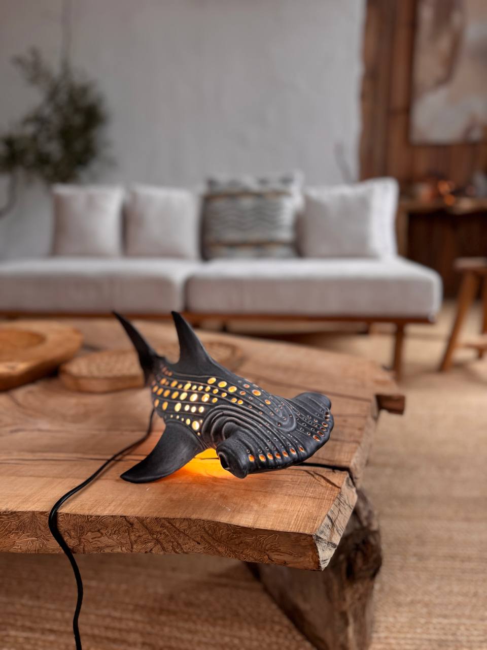 Decorative lamp shaped like a whale on a wooden table with a blurred living room background