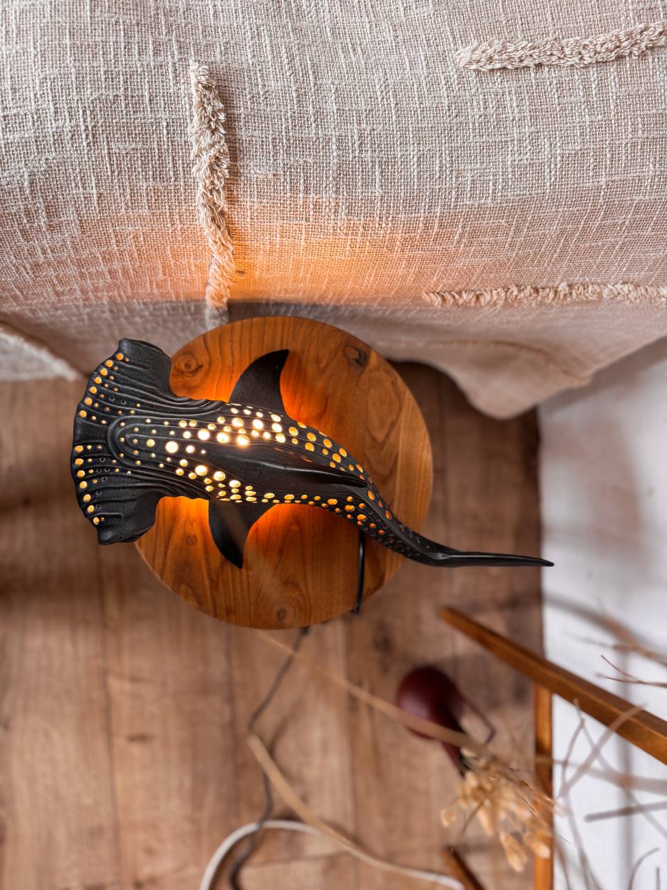 Decorative wall light shaped like a fish on a wooden surface with a neutral background